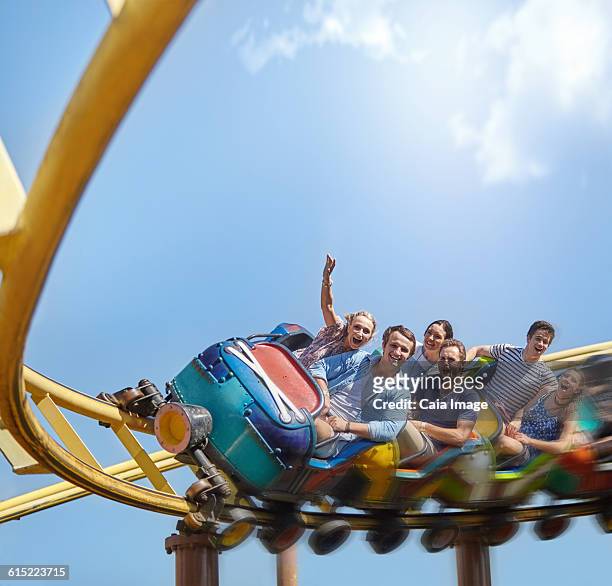 cheering friends riding roller coaster at amusement park - young woman screaming on a rollercoaster stock-fotos und bilder