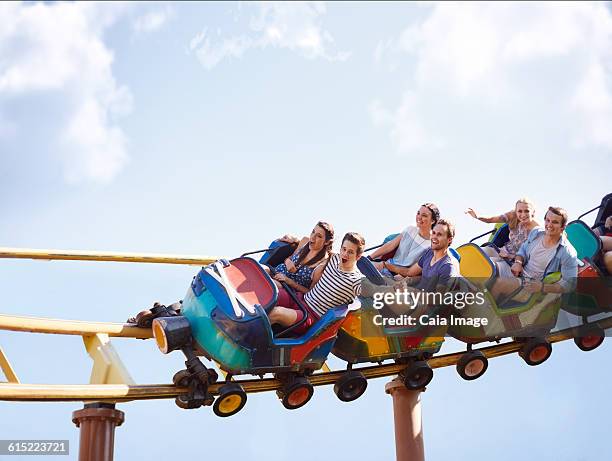 friends cheering and riding roller coaster at amusement park - young woman screaming on a rollercoaster stock pictures, royalty-free photos & images