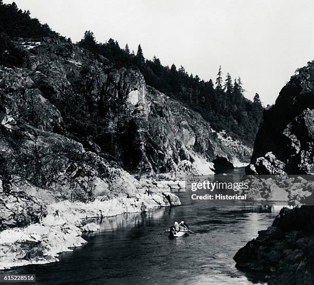 Trio of boaters row along the Rogue River in Oregon.