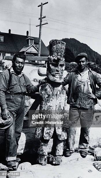 Tlingit Tribe assistant leaders Charles Brown, right, and James Starrish stand with the top of a totem pole carved to look like Abraham Lincoln. The...