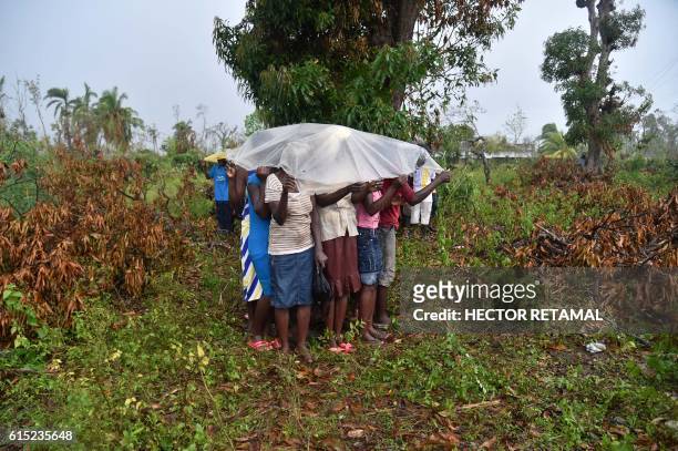 Hurricane Matthew victims cover themselves from the rain while they wait the start of delivery of food from the UN's World Food Programme in the...