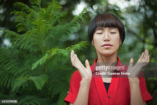 beautiful asian girl doing deep breathing exercise in nature. - deep breathing stock pictures, royalty-free photos & images