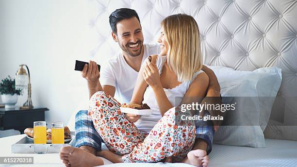 couple watching tv in bedroom. - confort at hotel bedroom stock pictures, royalty-free photos & images
