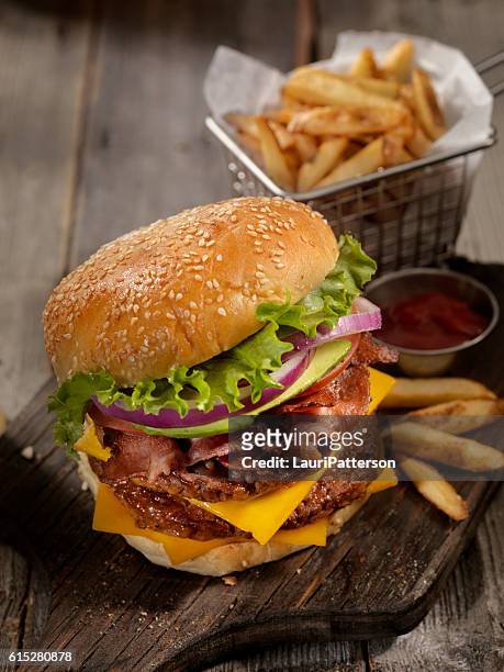 avocado bacon cheeseburger with a basket of fries - burger and fries stock pictures, royalty-free photos & images