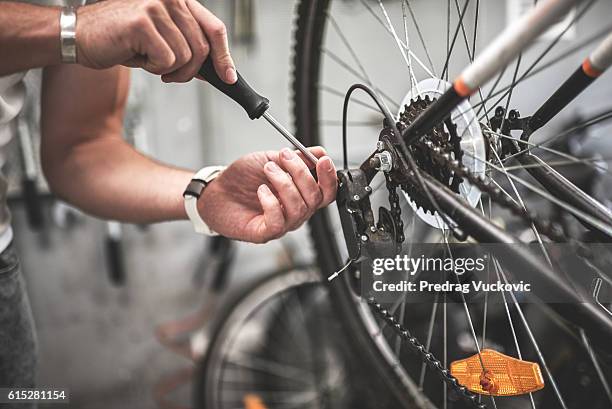 mechanic repairing bicycle rear wheel - reparatiewerkplaats stockfoto's en -beelden