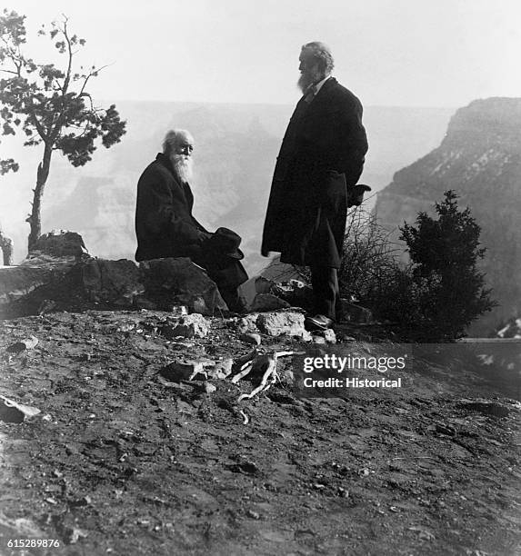 John Muir and John Burroughs stand on a mountain top. Muir was an American naturalist who campaigned for the establishment of Yosemite Park....