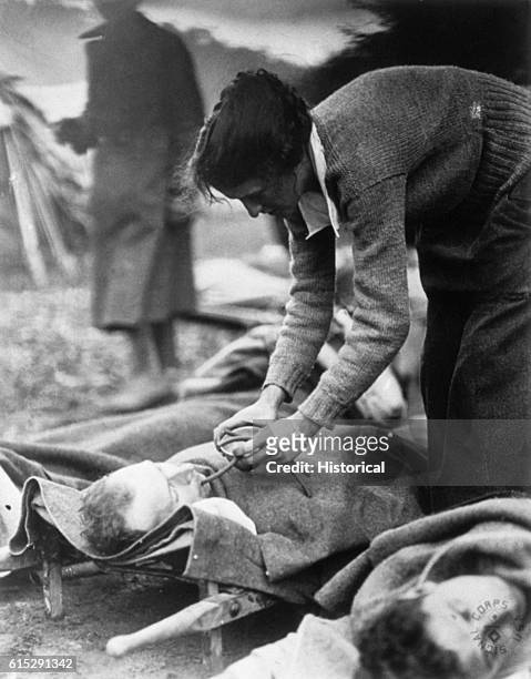 Red Cross worker Miss Anna Rochester of Smith College Unit fees a wounded soldier through a tube at U.S. Army Evacuation Hospital Nos. 6 and 7 in...