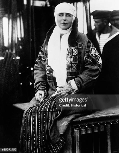 Queen Marie of Romania sits on a case while a sailor stands behind her. Marie was Queen of Romania with husband King Ferdinand from 1914 to 1927.