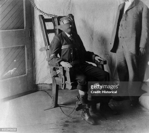 Man strapped into an electric chair awaits his execution by electrocution. United States, 1908.