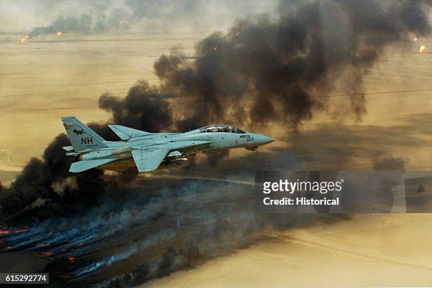 Fighter Squadron 114 F-14A Tomcat aircraft flies over oil well fires still burning in the aftermath of Operation Desert Storm, August 1991.