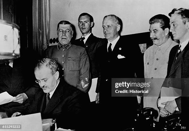 Russian leader Vyacheslav Molotov signs the Russo-German Non-Aggression Pact of August 1939 as Soviet premier Stalin and German foreign minister...