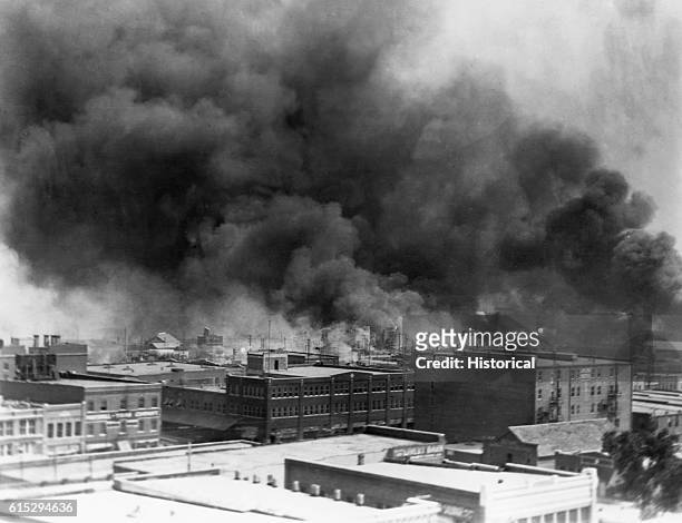 Black smoke billows from fires during the Tulsa Race Massacre of 1921, in the Greenwood District, Tulsa, Oklahoma, US, June 1921.