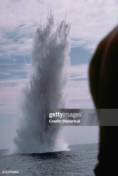 Geyser of water rises into the air following the detonation of a submerged mine by members of an explosive ordnance disposal team. | Location: near...