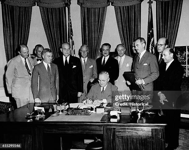 Surrounded by the ambassadors of various nations, President Harry Truman signs the North Atlantic Treaty.