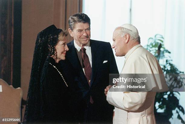 Pope John Paul II greets U.S. President Ronald Reagan and First Lady Nancy Reagan, on their visit to the Vatican. Mrs. Reagan wears a head covering...