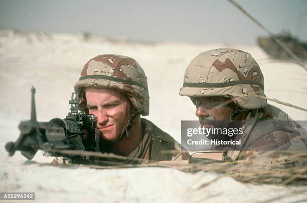 Two members of the 82nd Airborne Division observe a captured Iraqi MIL Mi-24 helicopter gunship from a distance during Operation Desert Storm. From...