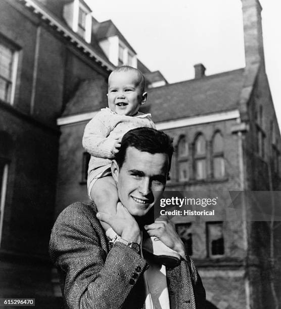 Future President George Bush carries his infant son George W. Bush on his shoulders on the Yale University campus. The younger Bush was elected...