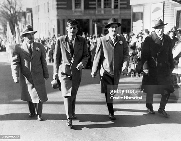 John F. Kennedy walks with three other men as he attends a St. Patrick's Day parade in south Boston.