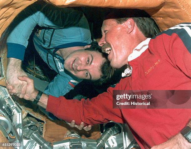 Robert L. Gibson , the mission commander of the Space Shuttle Atlantis, shakes hands with cosmonaut Vladimir N. Dezhurov, the commander of the Mir...