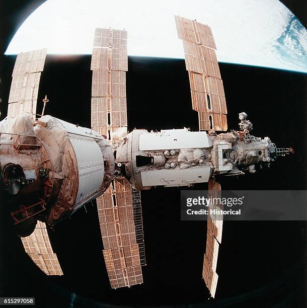 The Russian Space Station Mir in orbit above earth, as seen from the aft flight deck of the Space Shuttle Atlantis while it was linked-up with the...