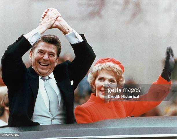 Ronald and Nancy Reagan waving and clasping hands in victory at Reagan's first inauguration, January 20, 1981.