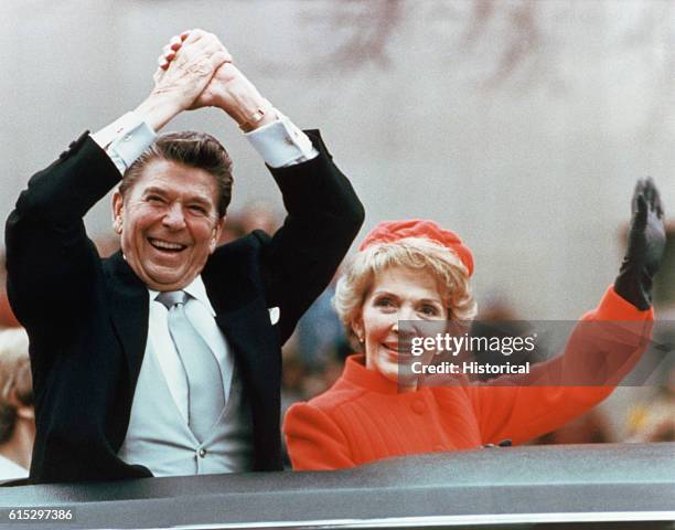 Ronald and Nancy Reagan waving and clasping hands in victory at Reagan's first inauguration, January 20, 1981.