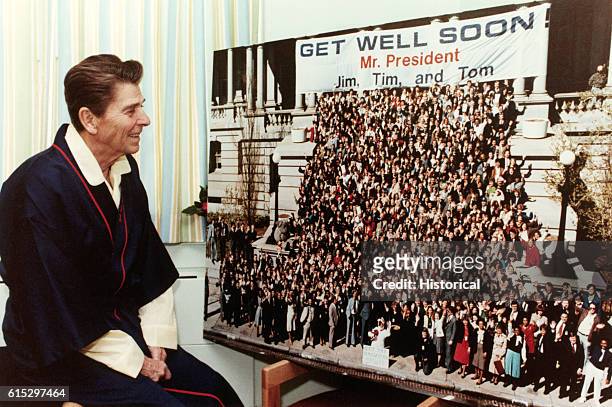 President Ronald Reagan views a giant get-well card while recuperating at George Washington Hospital from a gunshot wound suffered in an...