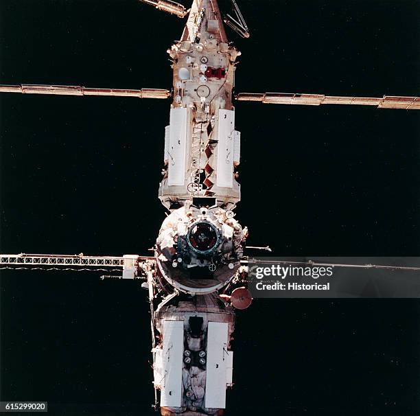 The Russian Space Station Mir in orbit above earth, as seen from the aft flight deck of the Space Shuttle Atlantis as it approaches for a link-up....