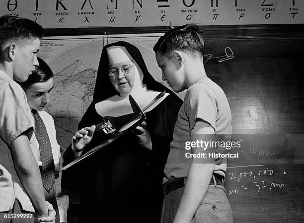 Sister Aquinas, the "flying nun", in their classroom at Catholic university looking over a student's model plane. Washington, DC, June 1943.