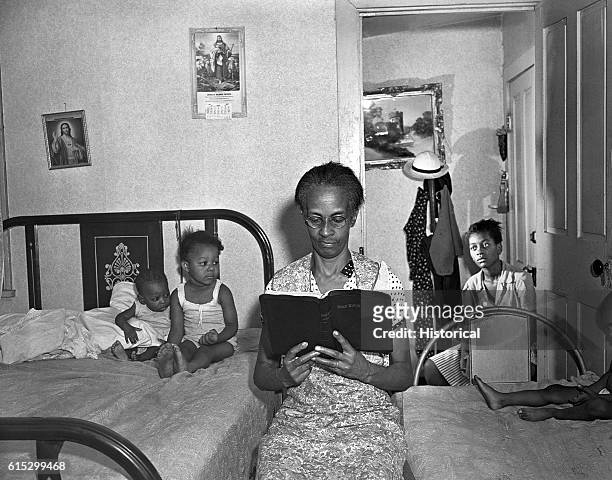 Ella Watson, a US government charwoman, reading the bible to her adopted daughter and three grandchildren. Washington, DC, August 1942.