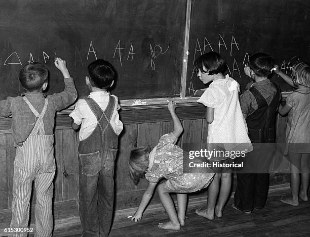 Children practicing writing the letter A on a kindergarten blackboard at Lake Dick, a Farm Security Administration project in Jefferson County,...