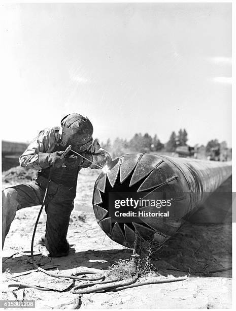 Worker making a bull nose plug in the casing for pipe going under railroad tracks in Texas. The pipe is part of the war emergency pipeline extending...