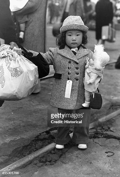 Japanese-American child waiting in Los Angeles, California, to go with his parents to Manzanar War Relocation Center, an internment camp in Manzanar,...