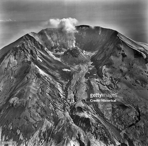 Steam rises from the growing lava dome of Mount Saint Helens. A narrow mud flow from a small eruption in late May descends from the dome. | Location:...