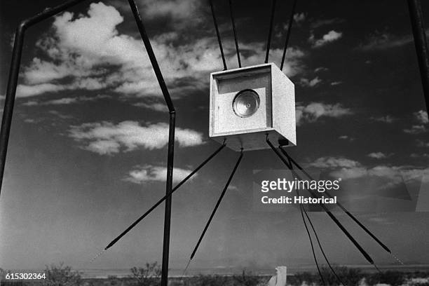 An excess velocity gauge suspended from a frame assists Manhattan Project scientists in nuclear weapons development and testing at the Trinity Site...