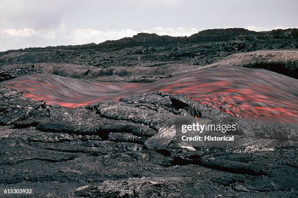 Channel of fast-flowing lava moves through a cooled section of a lava flow. Hawaii.