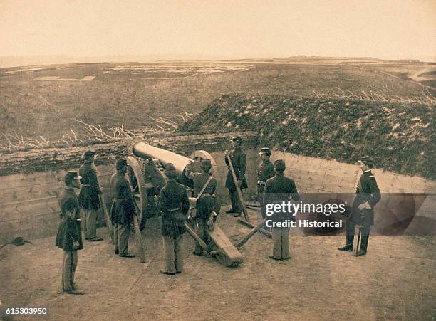 Abatis surrounds a gun emplacement where Union artillerymen pose at a cannon in northern Virginia during the American Civil War.