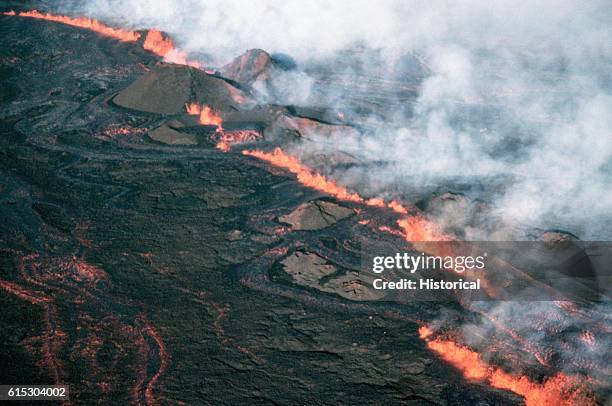Lava fountains form a red line in the center of a steaming lava flow. Hawaii.