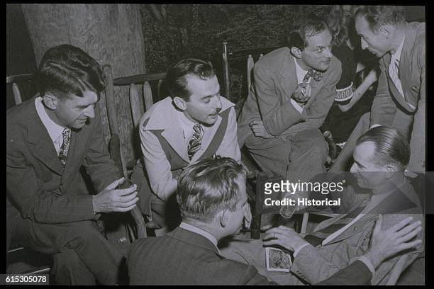 Group of men working on the Manhattan Project get together for an informal gathering. Stanislaw Ulam is talking to a man bent toward him; Edwin...