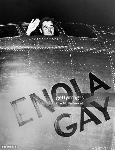 Colonel Paul W. Tibbets, Jr., pilot of the Enola Gay, waves from the cockpit before taking off on his mission to drop the atomic bomb on Hiroshima....