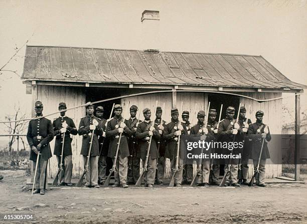 African American guards of the 107th United States Colored Troops pose putside a guard house at Fort Corcoran.