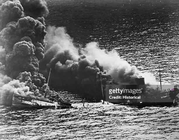 An allied tanker crumbles under the heat of fire after being torpedoed in the Atlantic Ocean by a German submarine. 1942.