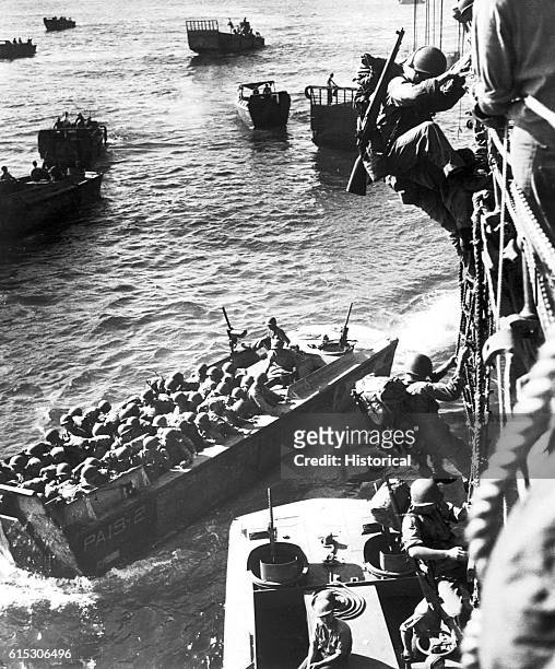 Troops go over the side of a Coast Guard manned combat transport to enter the landing barges at Empress Augusta Bay, Bougainville, as the invasion...