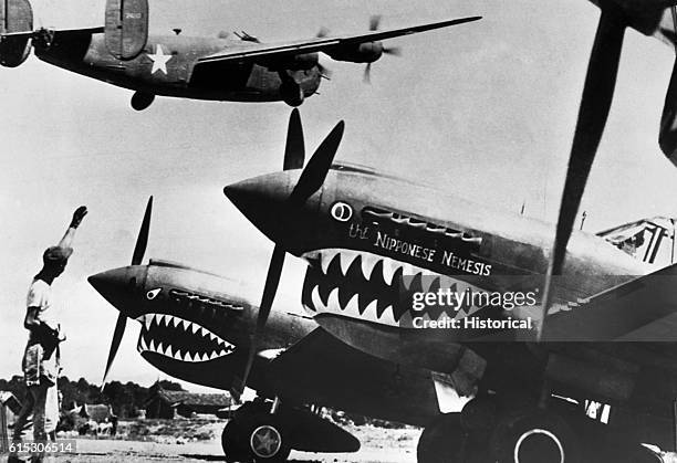 Bomber takes off for Japan above rows of Curtiss P-40 fighter planes painted with shark's teeth at a U.S. Base in China.