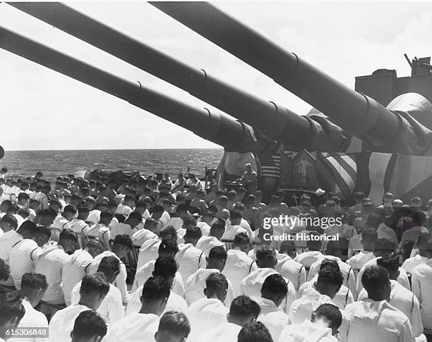 The crew of the USS South Dakota stands with bowed heads, while Chaplain N.D. Lindner reads the benediction held in honor of fellow shipmates killed...