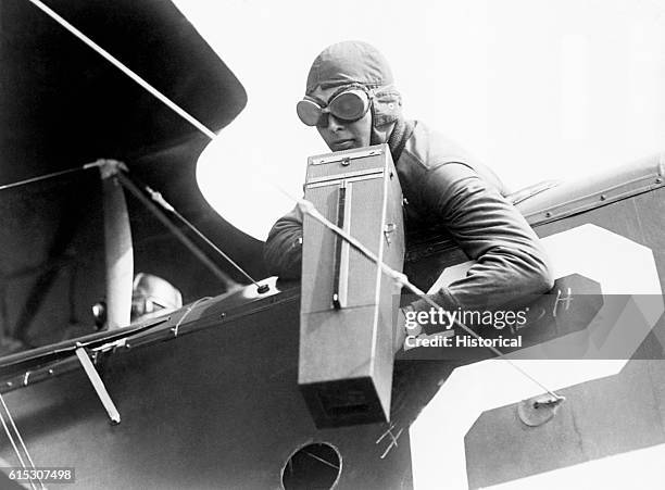 The co-pilot of a plane takes photograph using an Aeroplane Graflex camera in flight during World War I, ca. 1914-1918.
