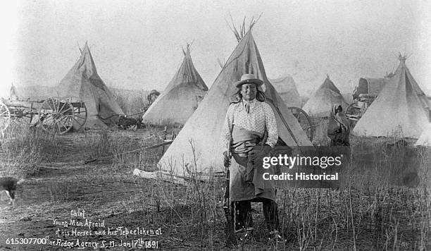 An Oglala Sioux, named Tashun-Kakokipa or Young-Man-Afraid-of-His-Horses, standing in front of his lodge at Pine Ridge, South Dakota on January 17,...