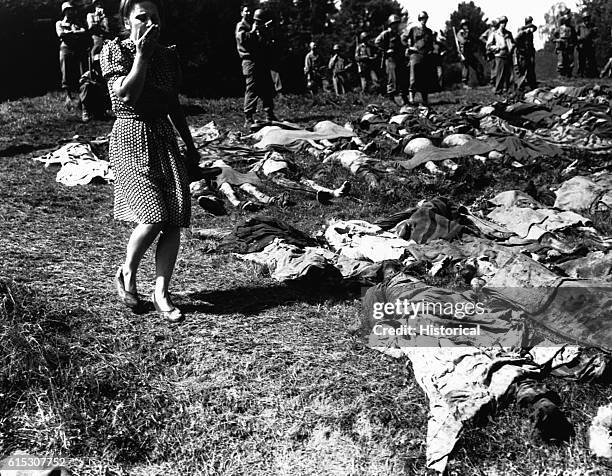 Young German woman is overcome as she walks past the exhumed bodies of some 800 slave workers murdered by SS guards near Namering, Germany, and laid...