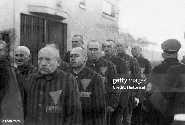 Prisoners in striped uniforms bearing triangular badges, on parade in Sachsenhausen Concentration Camp near Berlin, Germany, 19th December 1938. Nazi...