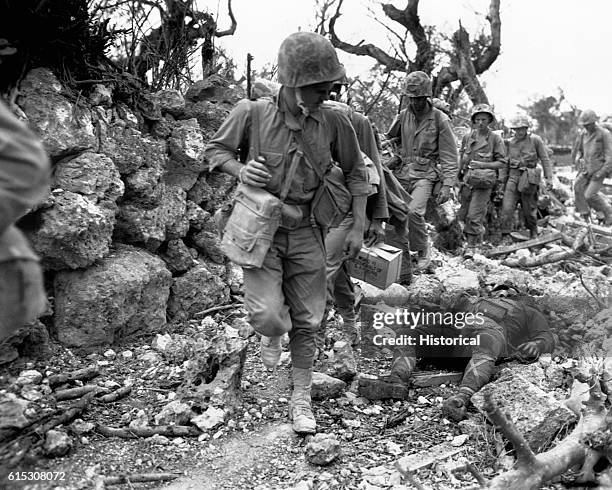 Marines pass through a small village where Japanese soldiers lay dead. Okinawa, April 1945.